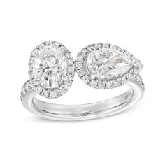 a white gold ring with two pear shaped diamonds on the sides and an oval halo style diamond