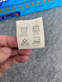 someone is holding up a piece of cloth with the symbols for washing machines on it