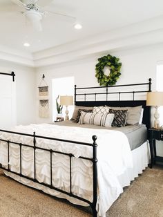 a bedroom with a bed, nightstands and a wreath on the wall above it