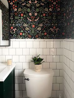 a white toilet sitting under a bathroom mirror next to a green cabinet and tiled wall