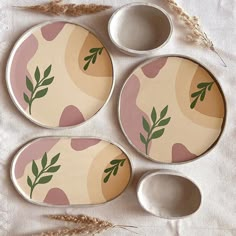 three plates and two bowls with leaves painted on them