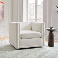 a white chair sitting on top of a rug next to a window