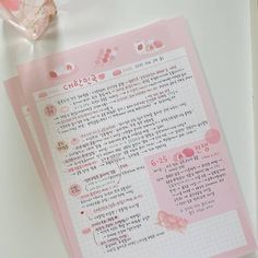 a piece of pink paper with writing on it next to a glass container and pen