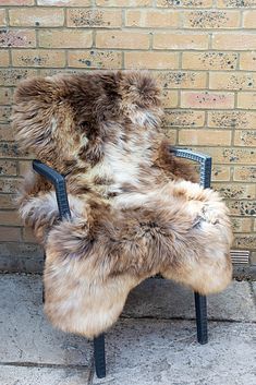 a chair that has some kind of fur on it and is sitting in front of a brick wall