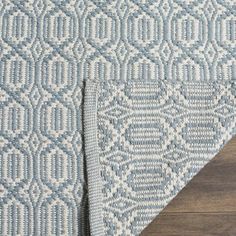 a blue and white rug on top of a wooden floor next to a piece of wood