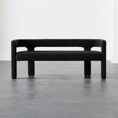 a black bench sitting on top of a cement floor in front of a white wall