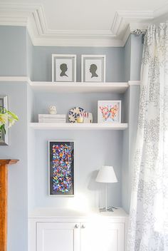 a living room filled with furniture and pictures on the wall next to a window covered in curtains