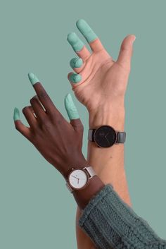 two hands with green manicures are holding each other's fingers and one has a watch on their wrist