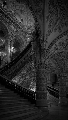 an ornate staircase with chandeliers and paintings on the walls in black and white