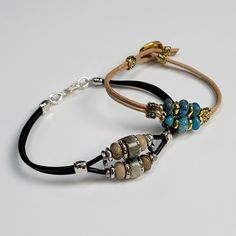 two bracelets with beads and charms are shown on a white surface, one has a black cord