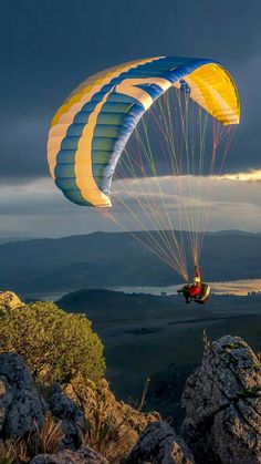 a person is parasailing over the mountains at night with dark clouds in the background