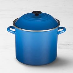 a blue casserole sitting on top of a white counter next to a black lid