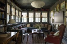 a living room filled with furniture and bookshelves next to a window covered in pictures