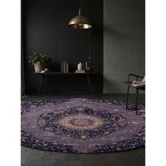 a round rug with an ornate design in purple and gold colors on a black floor