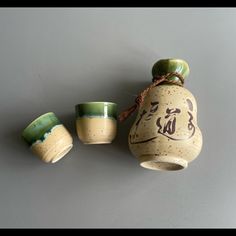 three ceramic cups with writing on them are sitting next to each other in front of a gray wall