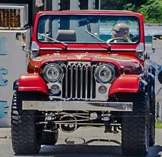 a red jeep is driving down the street