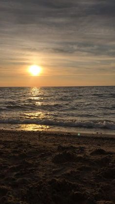 the sun is setting over the water at the beach