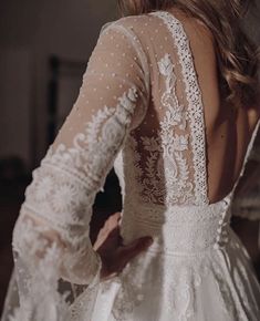 the back of a woman's wedding dress with sheer sleeves and beaded details