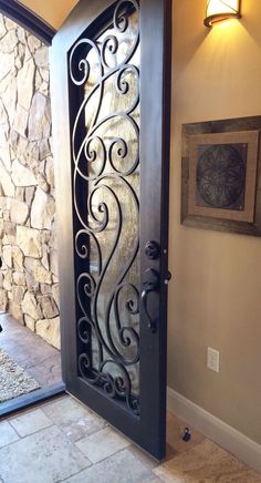 an ornate iron door is shown in the entry way to a home with stone walls and tile flooring