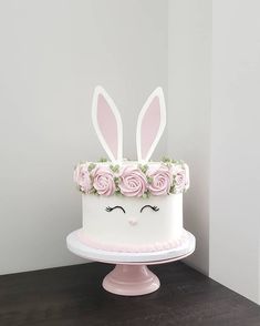 a cake decorated with pink roses and bunny ears