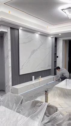 a man is working on the walls in a room with white marble and grey paint