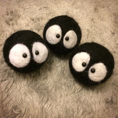 three small black and white stuffed animals on a furry surface, with eyes drawn out