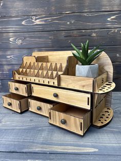 a wooden desk organizer with drawers and a potted plant