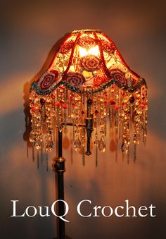 a lamp that is sitting on top of a wooden table next to a wall with the words louq crochet written below it