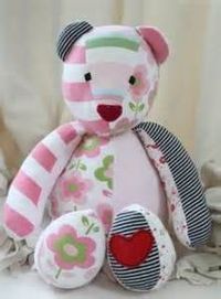 a pink teddy bear sitting on top of a white bed next to a window curtain