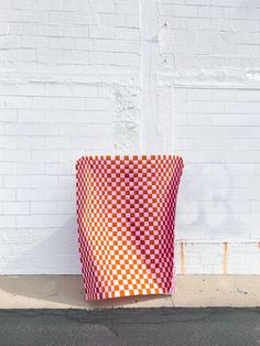 an orange and white checkered basket sitting on the side of a building