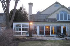 a house that is sitting in the middle of a yard with lots of windows on it