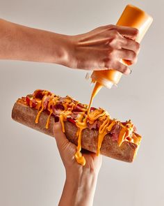 someone is pouring mustard onto a hot dog bun with ketchup and mustard on it