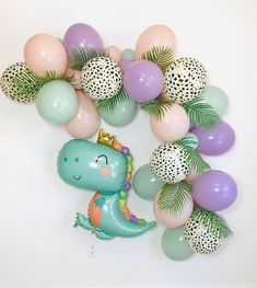 the balloon arch is decorated with pastel balloons and a dinosaur balloon for a baby's first birthday