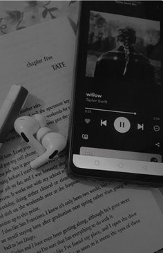 an mp3 player sitting on top of a book next to ear buds and headphones