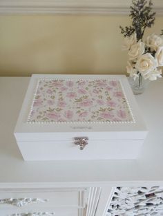 a white box sitting on top of a table with flowers in the vase next to it