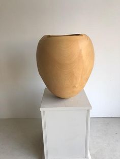 a wooden vase sitting on top of a white pedestal