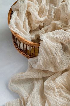 a wicker basket filled with white fabric