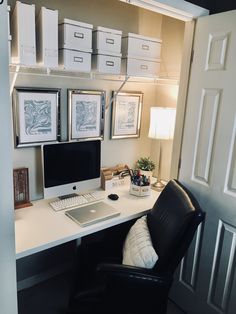 a desk with a computer on top of it next to a lamp and some drawers