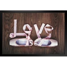 a pair of ballet shoes sitting on top of a wooden floor next to the word love