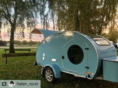 a small blue trailer parked on top of a lush green field