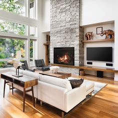 a living room with a large stone fireplace and white couches in front of a flat screen tv