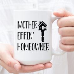 a person holding a coffee mug that says mother effin'n homeowner