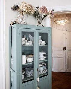 a china cabinet with plates and flowers on top