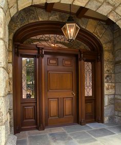 a wooden door with two sidelights on the top and bottom, in front of a stone building