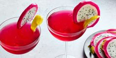 two wine glasses filled with dragon fruit and garnished with sliced lemon wedges