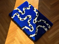 a blue rug with white and black designs on it sitting on top of a wooden floor