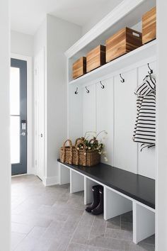 a black and white bench with two baskets on it's back, next to a wall mounted coat rack