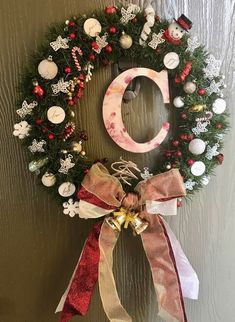 a christmas wreath with the letter o on it hanging on a door handle, decorated with ornaments and ribbons