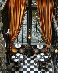 an outdoor dining area with black and white checkered flooring, gold drapes, and chairs