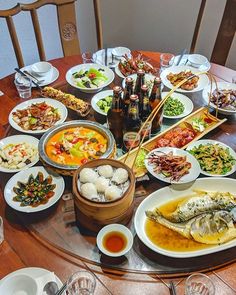 a table full of food with chopsticks and wine glasses on the top one